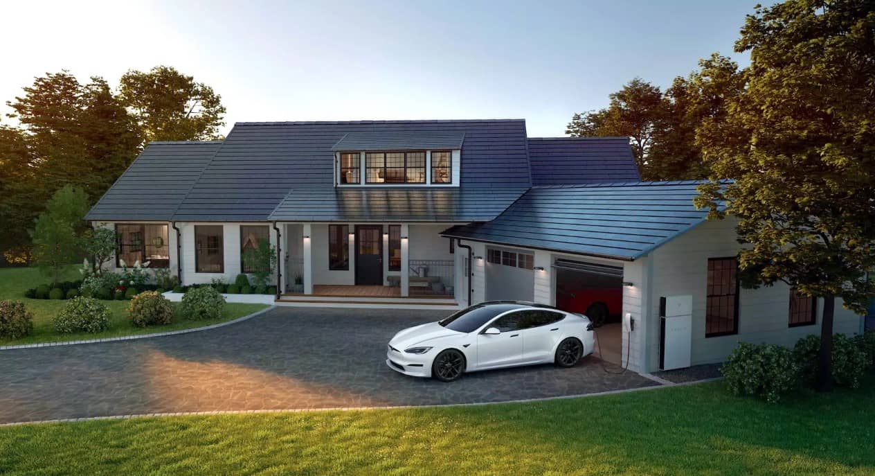 A modern house with solar roof tiles, a white electric car parked in the driveway, a landscaped yard, and trees surrounding the home at sunset.